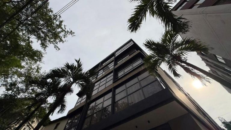 Fachada exterior moderna del Autenthico Atempo Local Suites Medellín rodeada de palmeras y árboles tropicales