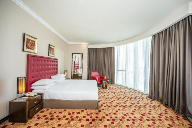 Habitación deluxe con cama king size y cabecero rojo en Kingsgate Hotel Doha by Millennium Hotels