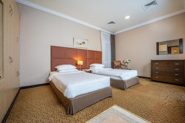 Habitación twin con dos camas y cabecero marrón en Kingsgate Hotel Doha by Millennium Hotels