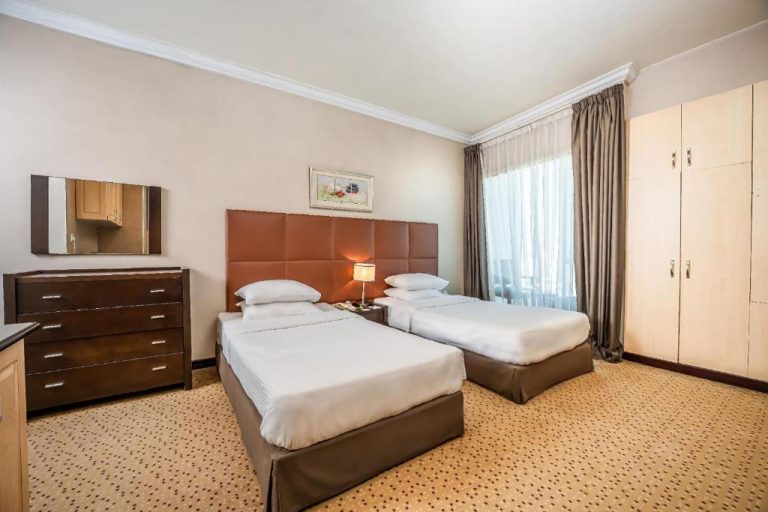 Habitación twin con dos camas y cabecero marrón en Kingsgate Hotel Doha by Millennium Hotels