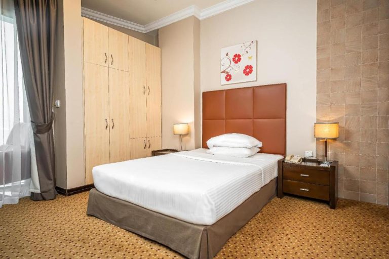Habitación doble con cabecero marrón y armarios de madera en Kingsgate Hotel Doha by Millennium Hotels
