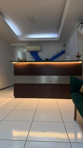 Recepción moderna con mostrador iluminado y decoración en azul del Hotel Sol Brasil