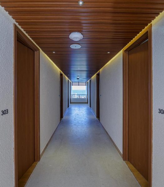 Pasillo interior con techo de madera y puertas de habitaciones en el Hotel Kinan Sentral