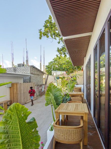 Terraza exterior con mobiliario de madera y vegetación tropical en el hotel Kinan Sentral