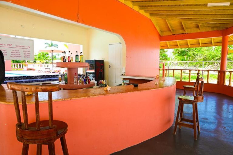 Bar tropical con taburetes de madera y mostrador curvo en Shields Negril Villas, Jamaica