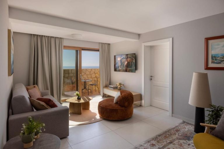Salón luminoso con sofá, sillón y balcón con vistas al mar en el Palace Natali