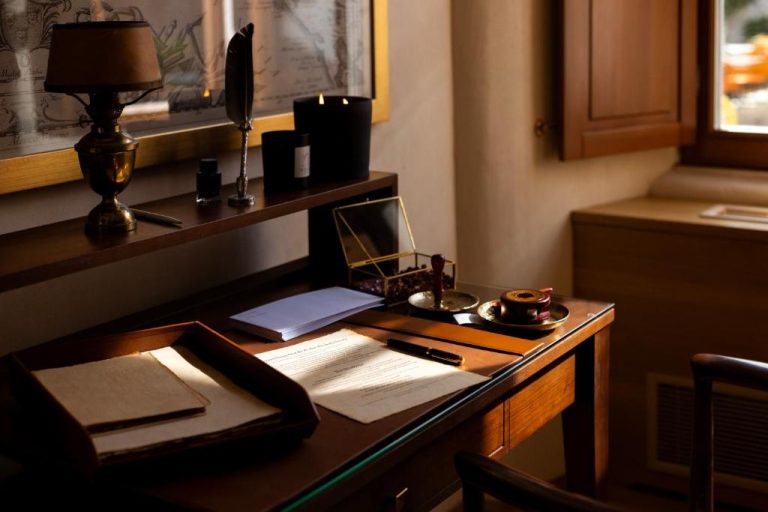 Escritorio clásico de madera con pluma, documentos y vela en suite del Palace Natali