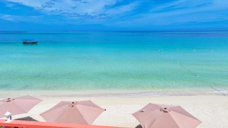 Playa de arena blanca con aguas turquesas cristalinas y sombrillas en Shields Negril Villas, Jamaica