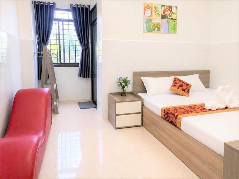 Habitación doble con cama matrimonial, silla roja y ventana con cortinas azules en Viora Hotel
