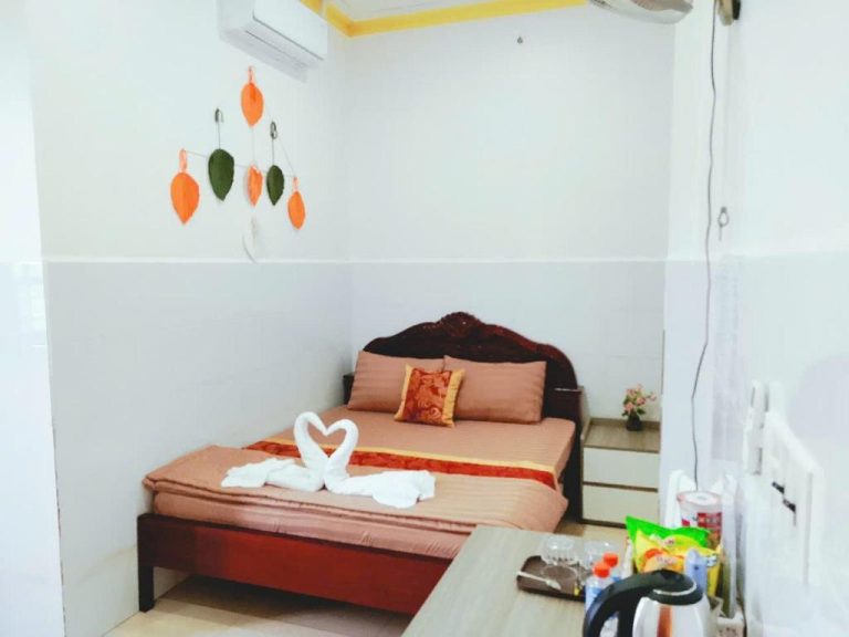 Habitación doble del Viora Hotel con cama decorada con cisnes de toalla y adornos de hojas en la pared