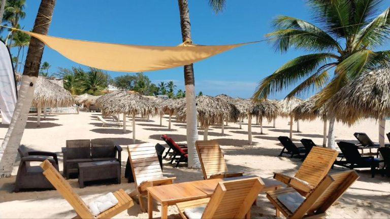 Zona de playa con tumbonas, sombrillas de palma y vela de sombra en Beach Garden Club Punta Cana