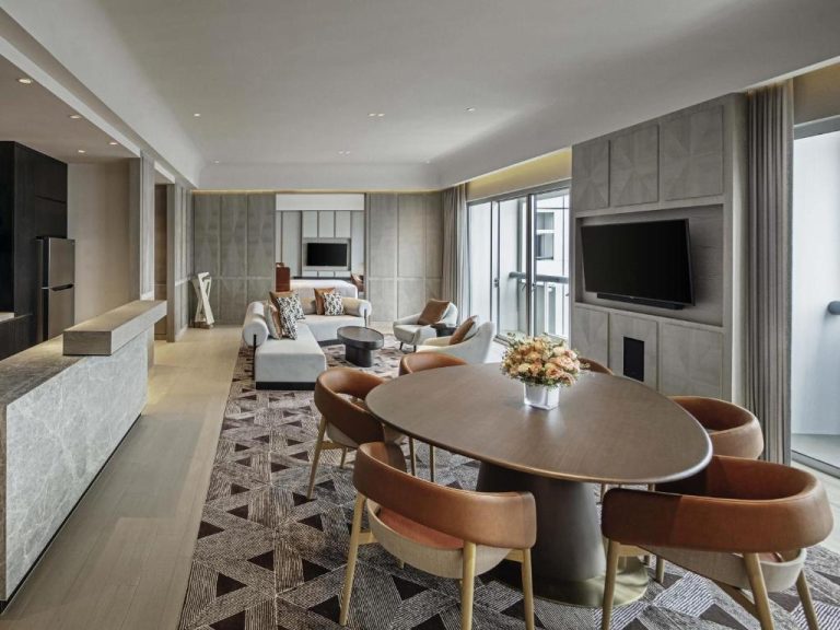 Amplio salón comedor de suite de lujo en Fairmont Singapore con mesa oval y sofás modernos