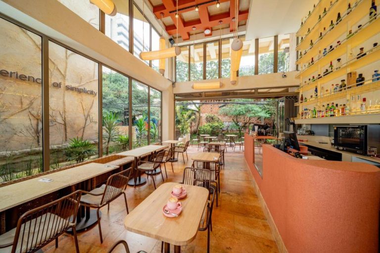 Cafetería interior con terraza abierta y bar de cócteles del Moabi Hotel rodeado de vegetación