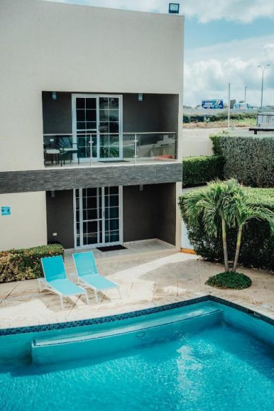 Piscina exterior con tumbonas azules y terraza privada del Hotel RH Boutique Aruba