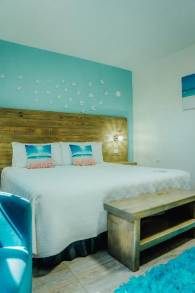 Habitación con cama doble y decoración tropical turquesa en Hotel RH Boutique Aruba