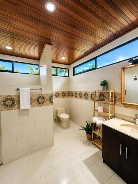 Baño moderno con techo de madera, azulejos decorativos y ventanales en Hotel Villas de la Colina