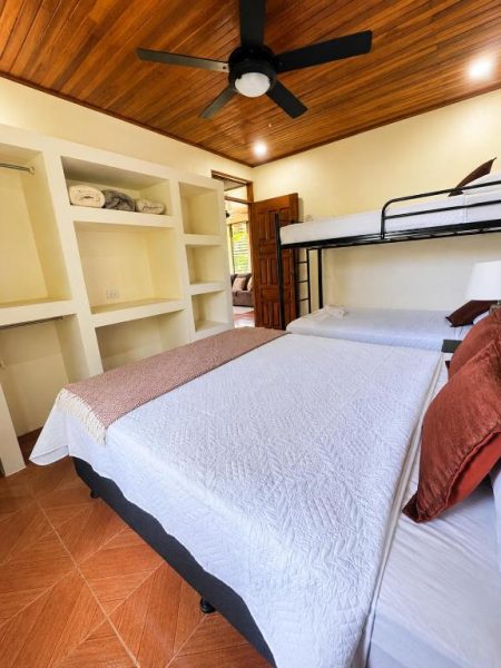 Habitación familiar con cama doble y litera metálica en Hotel Villas de la Colina con techo de madera