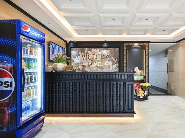 Recepción elegante con mostrador oscuro y nevera Pepsi en Victory Hotel Saigon South