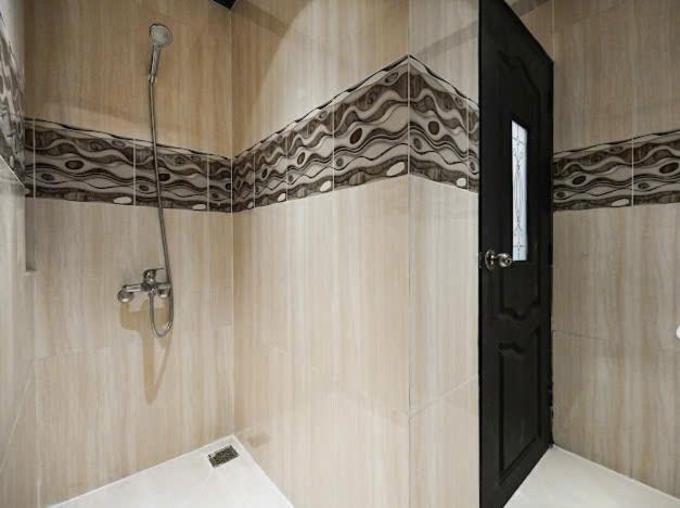 Baño con ducha de teléfono y azulejos decorativos en Victory Hotel Saigon South