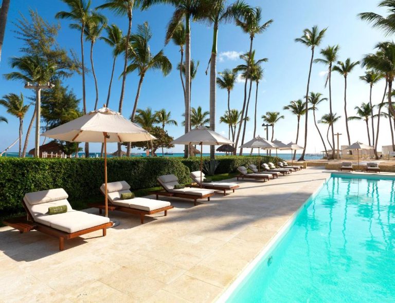 Piscina exterior con tumbonas y sombrillas junto a palmeras en Meliá Punta Cana Beach Resort