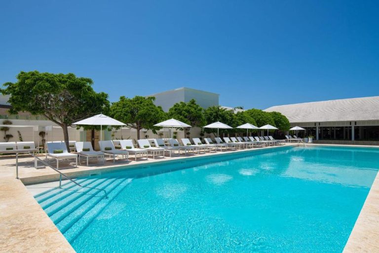 Piscina exterior con tumbonas y sombrillas blancas del Meliá Punta Cana Beach Wellness Inclusive Resort