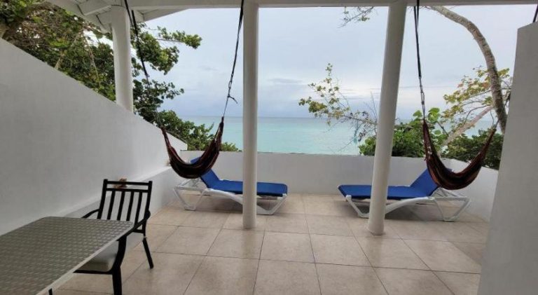 Terraza con hamacas y tumbonas con vista al mar turquesa en Merrils Deluxe