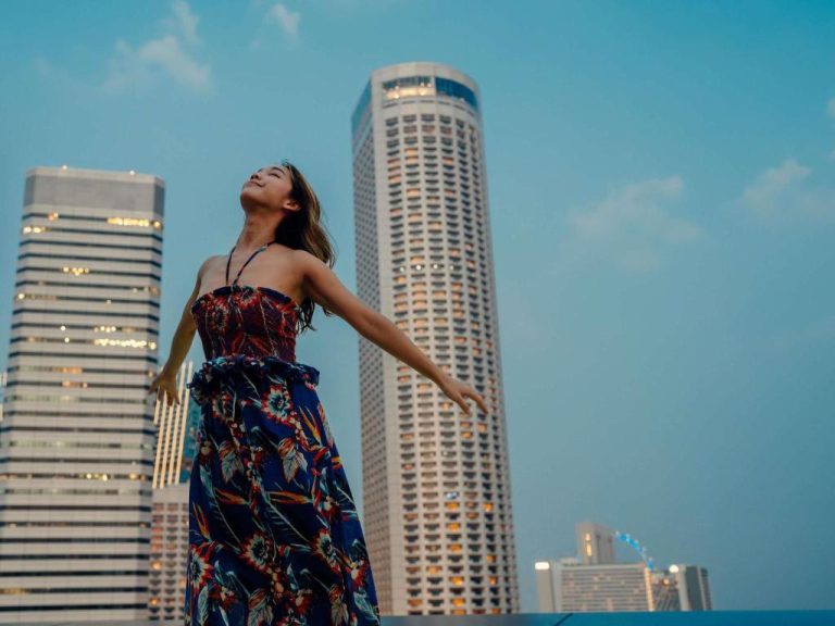 Mujer posando con el skyline del Swissotel The Stamford Singapore al atardecer con vistas a los rascacielos