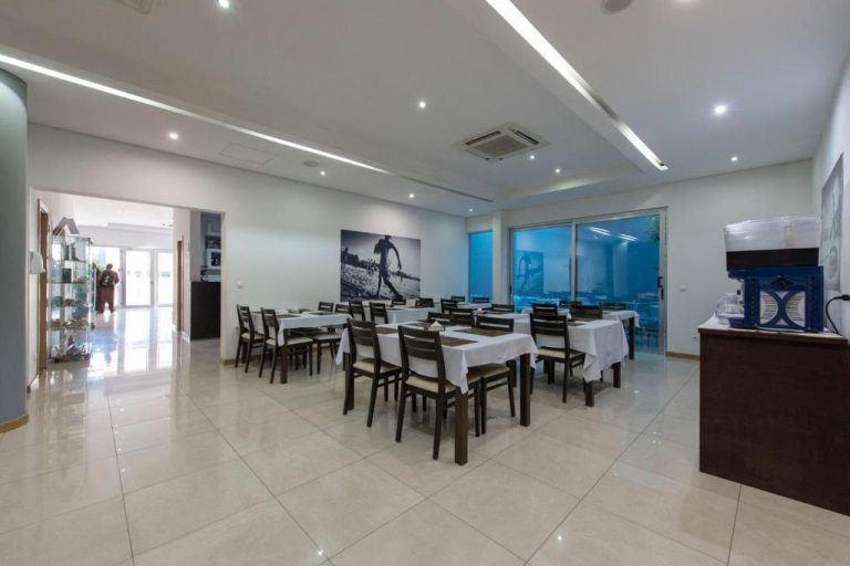 Comedor interior del Hotel Santiago con mesas preparadas, sillas de madera y grandes ventanales