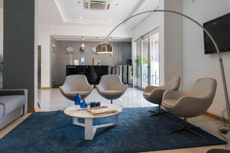 Recepción y sala de espera moderna del Hotel Santiago con sillones grises y alfombra azul