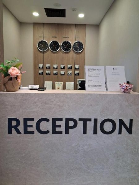 Recepción moderna del Central Plaza Hotel con relojes mundiales y mostrador de mármol en Sofia