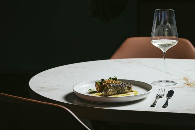 Plato de pescado gourmet con copa de vino blanco en el restaurante del Octant Ponta Delgada