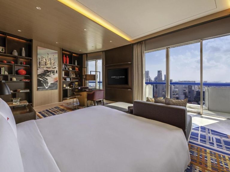 Habitación de lujo con cama king y vistas panorámicas a los rascacielos en Swissotel The Stamford Singapore