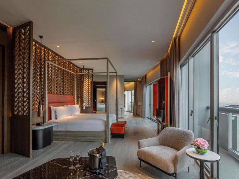 Suite de lujo con cama con dosel y amplia terraza con vistas panorámicas en Fairmont Singapore