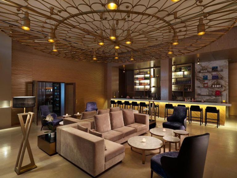 Elegante bar lounge con sofás de terciopelo y barra iluminada en Paradisus by Meliá Grand Cana All Inclusive