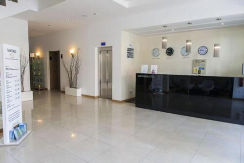 Recepción y lobby principal del Hotel Santiago con mostrador negro y relojes mundiales en la pared