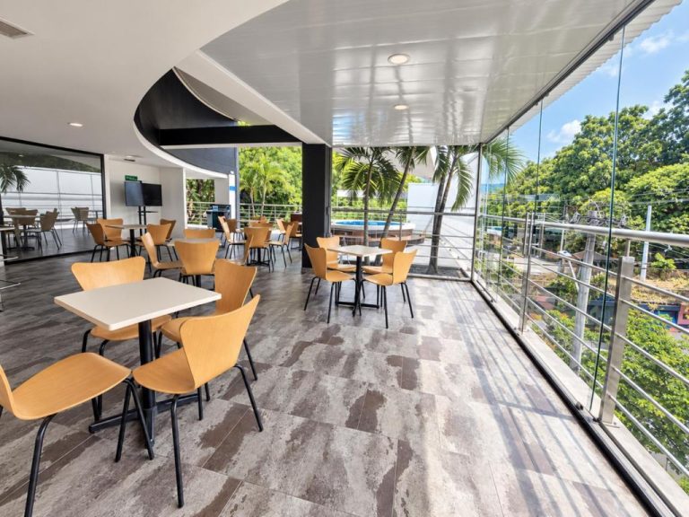 Restaurante con terraza acristalada y vistas tropicales del Hotel Med 33, mesas y sillas modernas