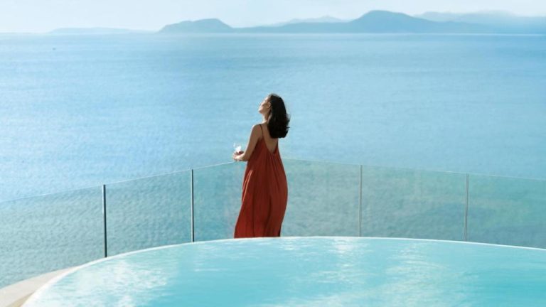 Mujer con vestido rojo junto a la piscina infinita con vistas al mar del Gabbiano Azzurro Hotel & Suites