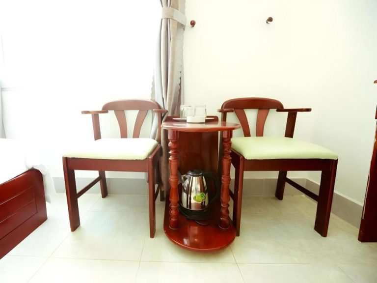 Mesa redonda de madera con dos sillas y tetera eléctrica en habitación del Xuan Hung Hotel