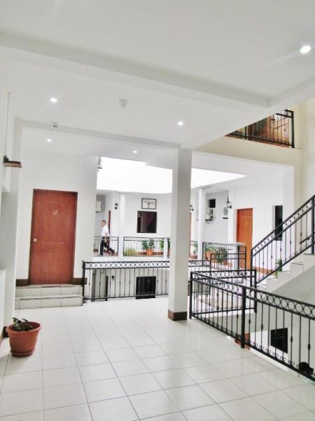 Amplio vestíbulo interior con escaleras y balcones del Hotel Palmeras de Elim